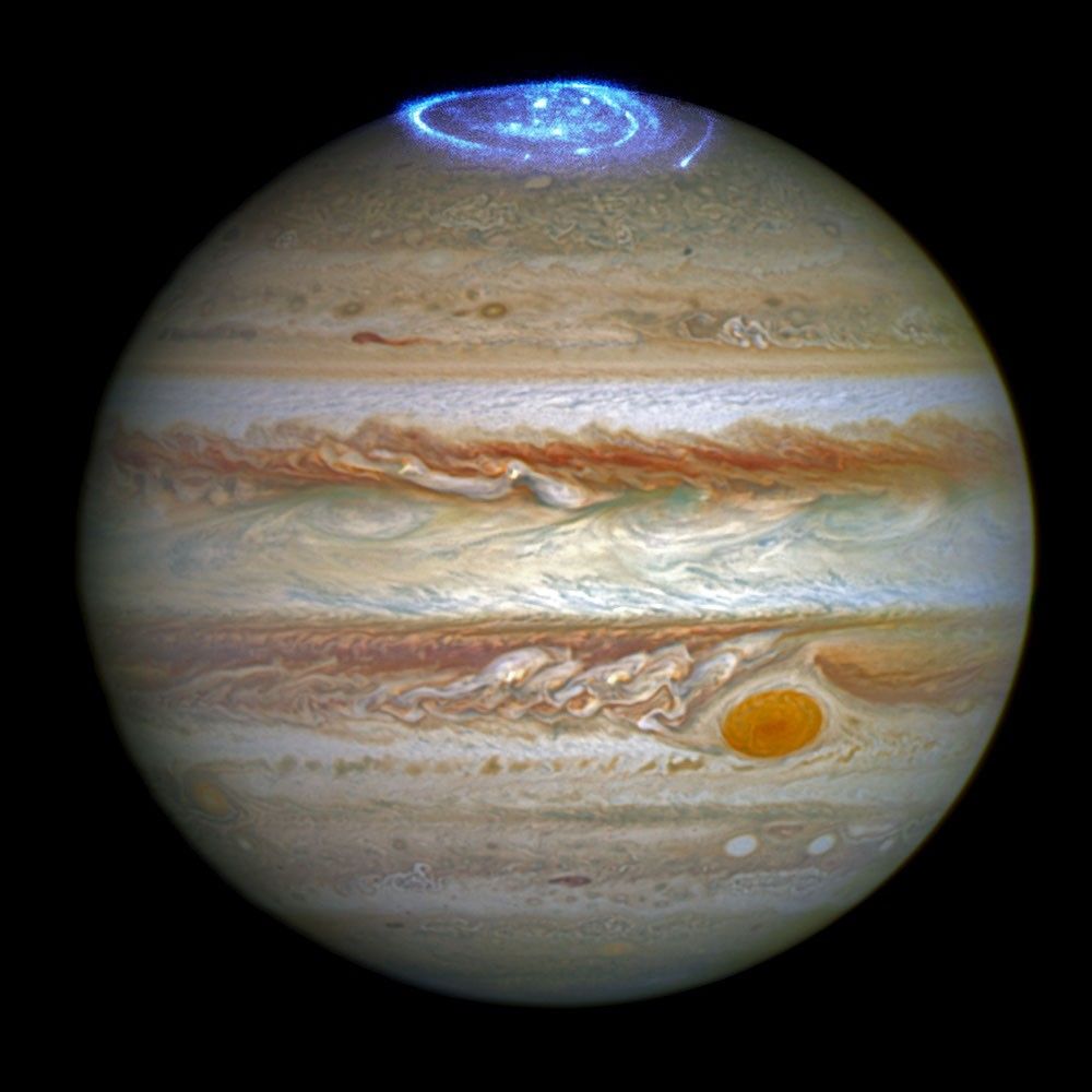 Framed image of the planet Jupiter, a sphere with horizontal stripes of brown, tan, orange, beige, light blue, and white against a solid black background.