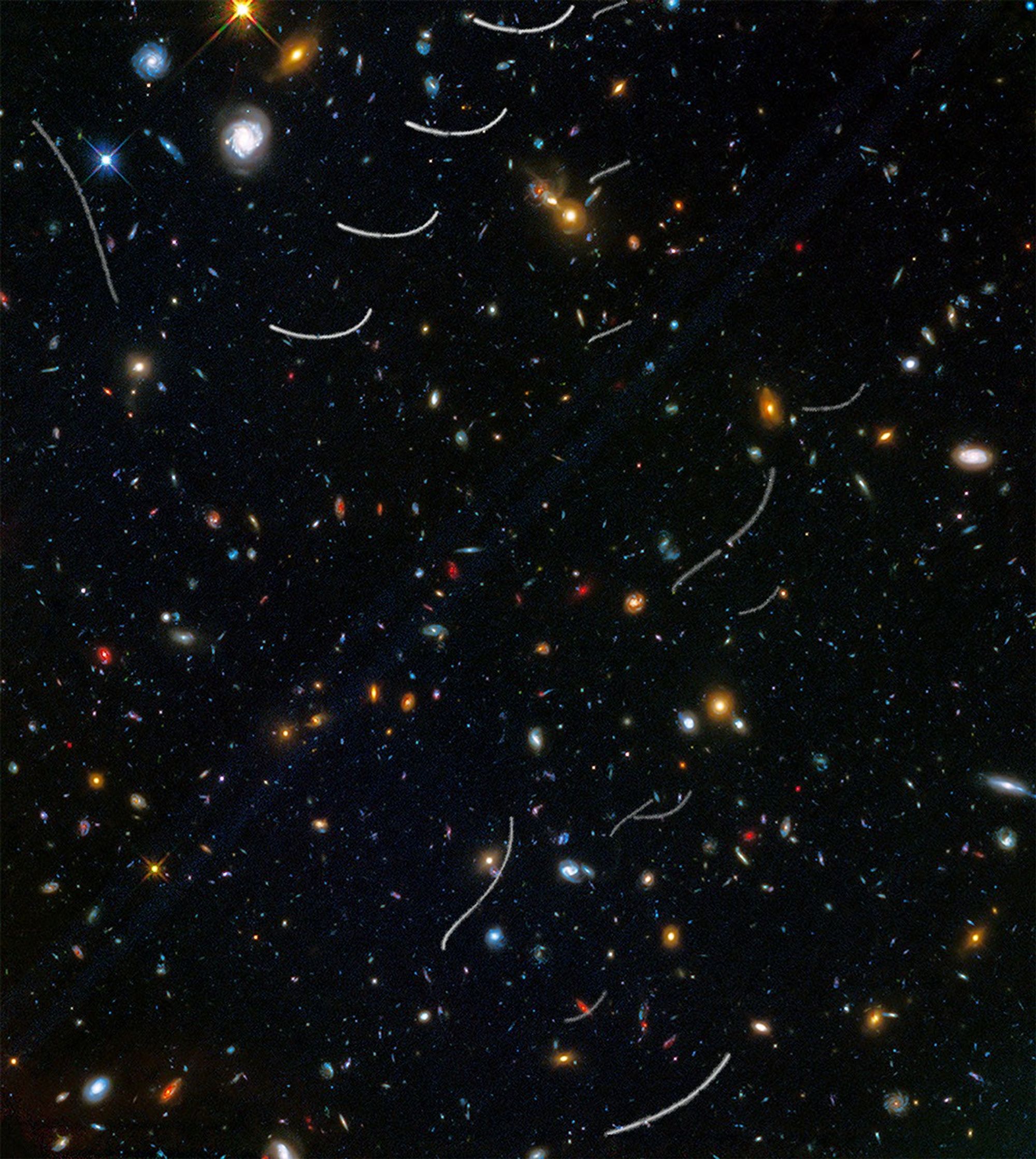 Hundreds of galaxies of various colors and sizes are scattered across the view, and about a dozen curved or wavy white streaks appear in random locations.