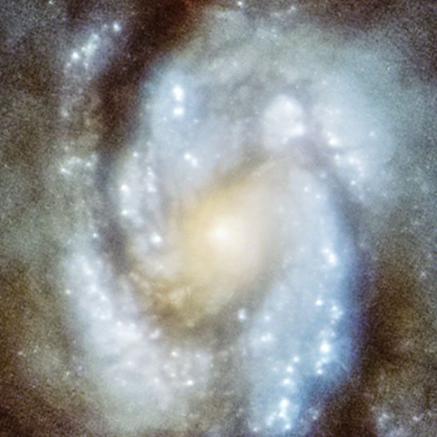Image by the Hubble Space Telescope’s Wide Field/Planetary Camera 1 showing the bright central core of spiral galaxy M100. The overall image is blurry and bright.