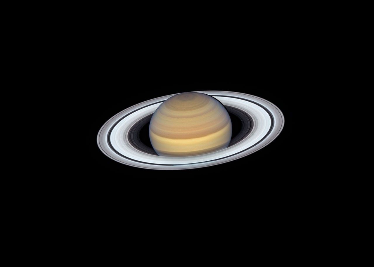 A view of Saturn from the Hubble Space Telescope captures exquisite details of the ring system, which looks like a white phonograph record with grooves that represent detailed structure within the rings.