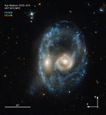 Galaxy merger—with compass arrows, scale bar, and color key for reference—that resembles the face of a mystical life form with glowing yellow eyes.