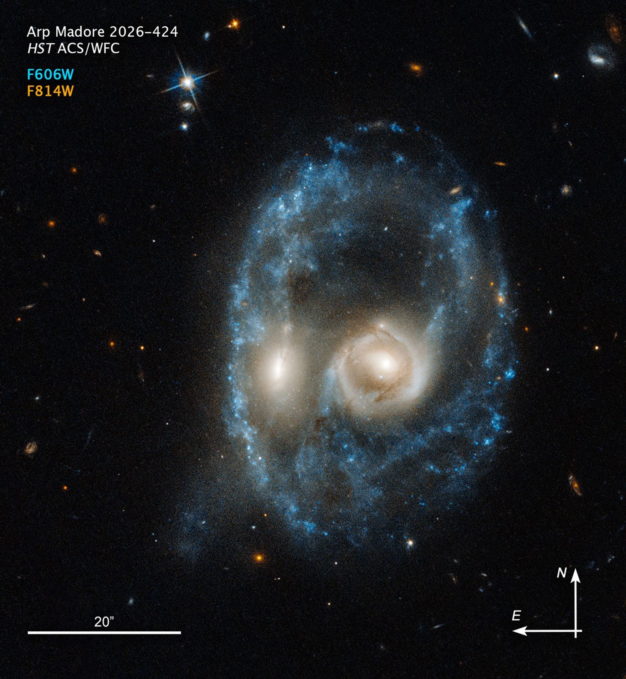 Galaxy merger—with compass arrows, scale bar, and color key for reference—that resembles the face of a mystical life form with glowing yellow eyes.