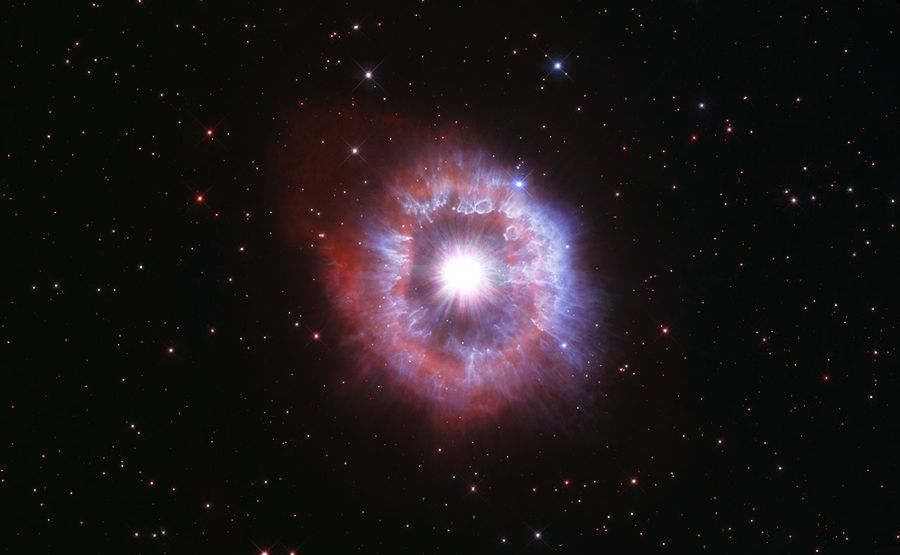 Bright star surrounded by kaleidoscopic rings of red and blue.