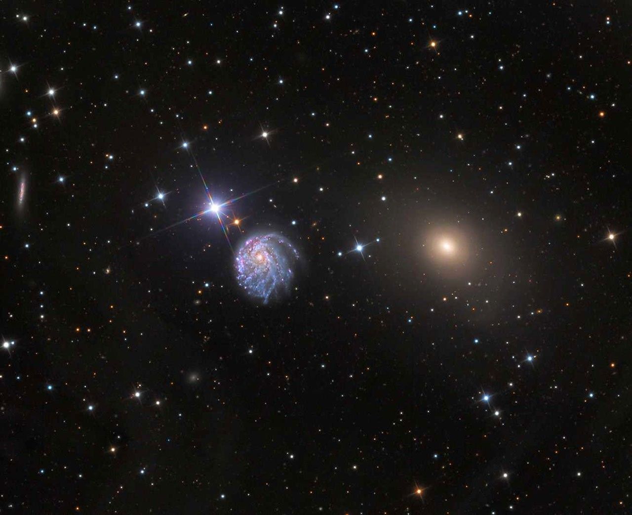 On a black, starry background are three bright objects in a horizontal row at the center: a bright star, a large spiral galaxy, and a smaller yellow galaxy.