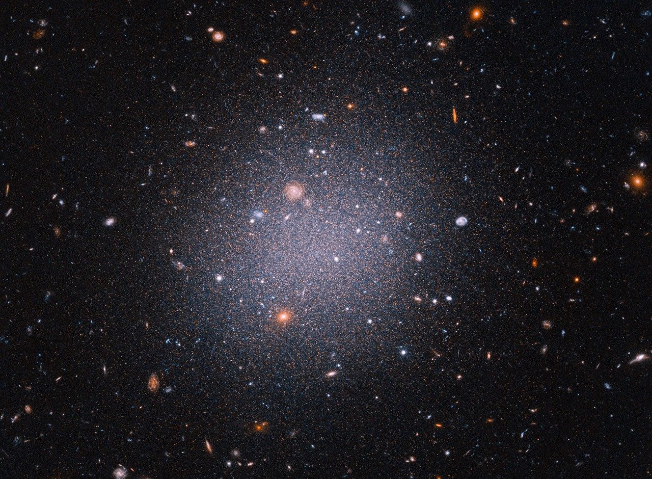 Diffuse galaxy with red giant stars and background galaxies