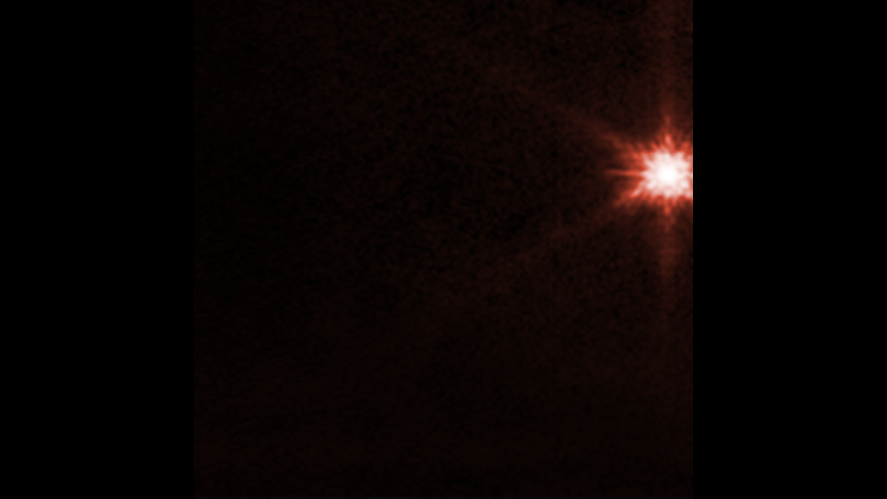 On a black background, a bright spot appears on the edge of the top right, with only 5 diffraction spikes show on its top, bottom and left side. The spot appears to get larger with many spikes of light emitting from it, as the asteroid is impacted by the spacecraft. Afterward, wisps of material stream away to lower left.