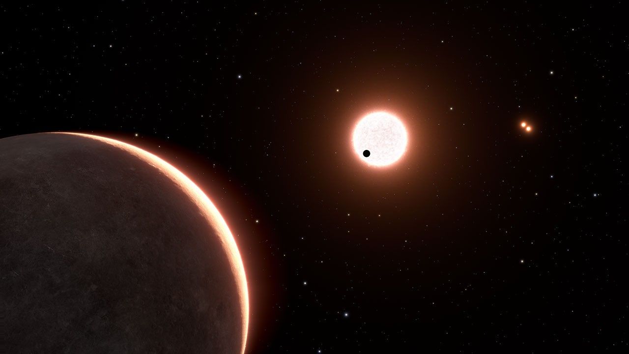 Artist's concept of nearby exoplanet LTT 1445Ac, which is the size of Earth. The rocky planet appears as a small black dot against a bright light-red sphere at image center. The star is in a triple system, with two closely orbiting red dwarfs — a pair of red dots — seen at upper right. Another exoplanet in the system, LTT 1445Ab is in the foreground at lower left.