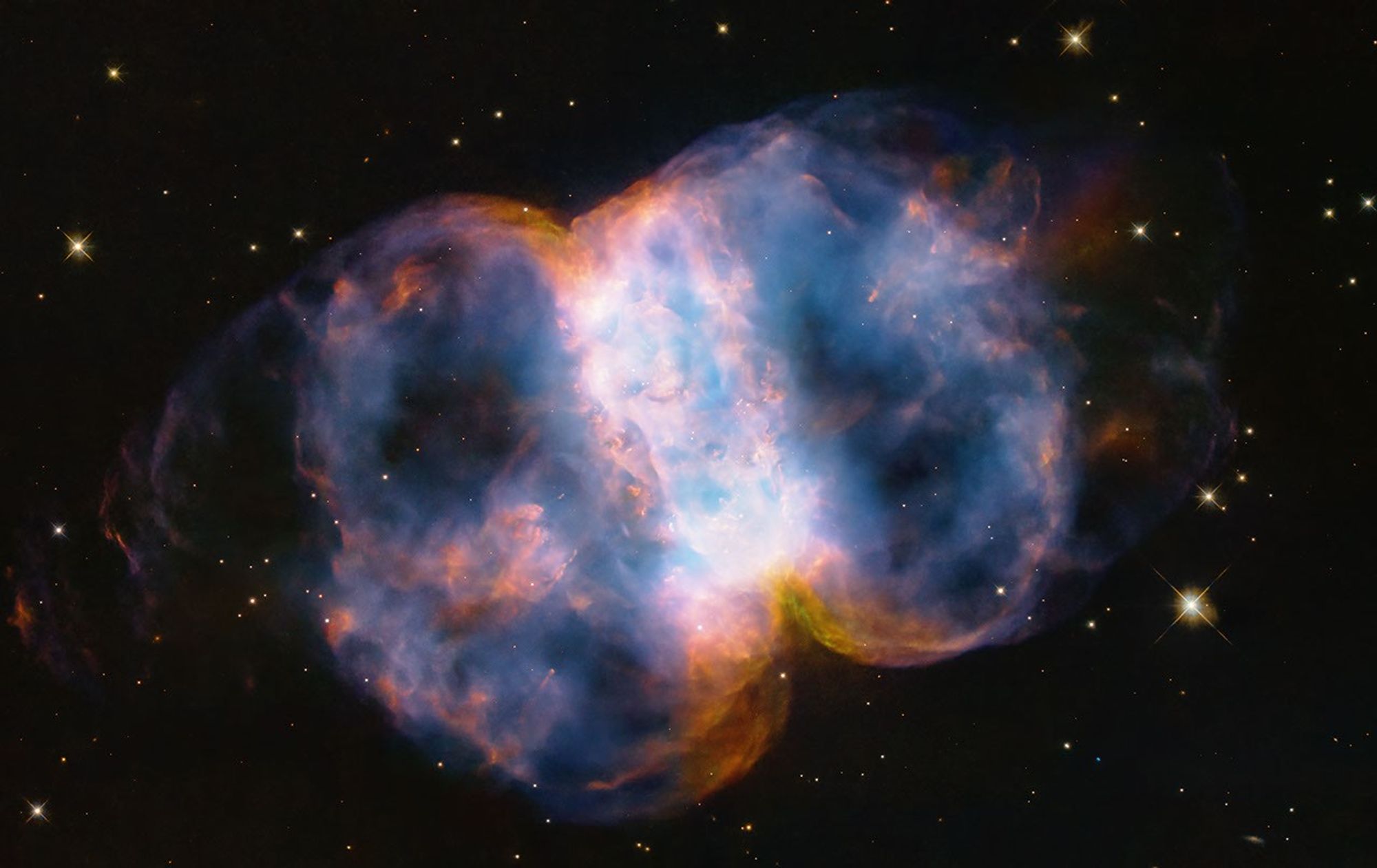 Taking up most of the image, is a multi-colored nebula appearing as two translucent orbs attached by a white band.