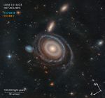 A graphic labeled “LEDA 1313424, HST ACS/WFC.” At the center is a large galaxy with a significantly smaller galaxy to its center-left on the black background of space.