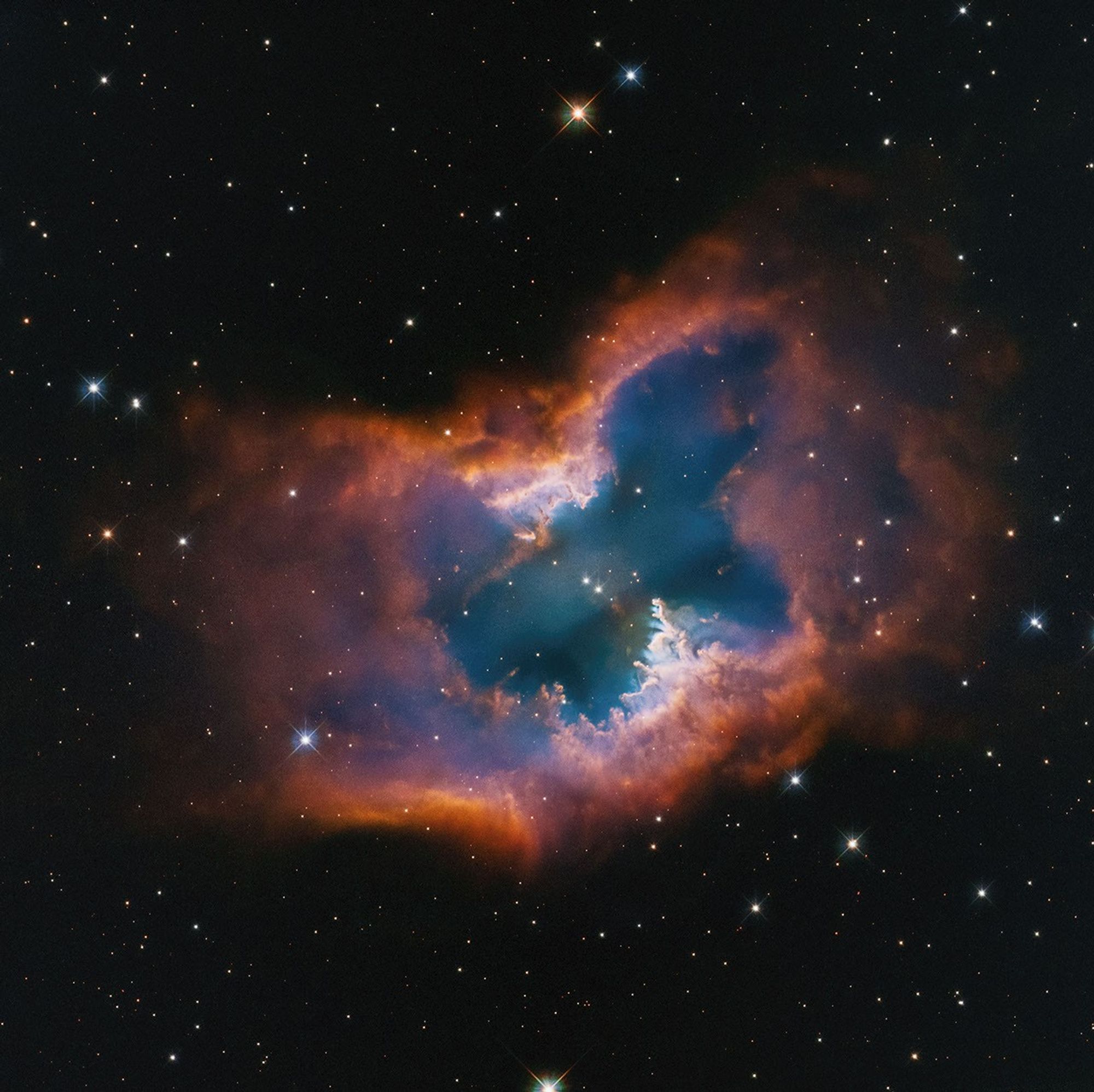 NGC 2899 set against the black background of space. The planetary nebula is shaped like a single macaroni noodle, with its edges pointed up, but its edge-on central torus is semi-transparent in the middle.