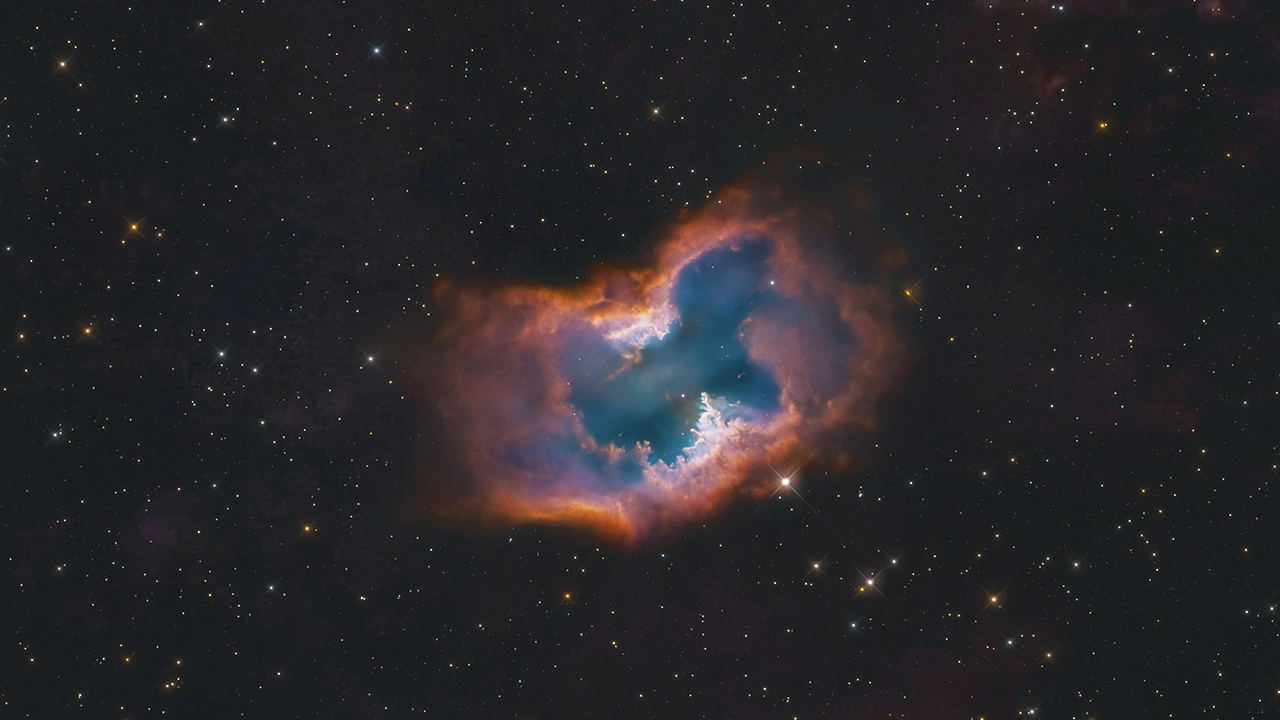 NGC 2899 set against the black background of space. The planetary nebula is shaped like a single macaroni noodle, with its edges pointed up, but its edge-on central torus is semi-transparent in the middle.