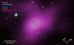 An image labeled u201cCloud 9 HST ACS WFCu201d. Below that, a color key shows F606W in blue, F814W in orange, and Radio VLA in purple. A region of space mostly filled with background galaxies, with one prominent star at upper left. A large blob of purple haze occupies much of the field. Within the purple region, an unremarkable area is outlined with a dashed white circle. At lower left, a scale bar extending about one-sixth of the image is labeled 2,000 light-years and 30 arcseconds. At lower right are compass arrows with east pointing to 10 ou2019clock and north pointing to 2 ou2019clock.