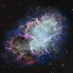 A colorful nebula of thick filaments of cosmic dust and gas appears to splash outward from a hazy white center. Colors include bright pink, blue, and orange. Small white stars dot the background.