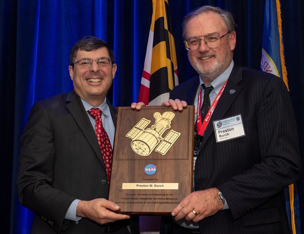 Scolese (left) and Burch (right) hold a wooden plaque between them with Burch's name and a gold graphic of Hubble on it.