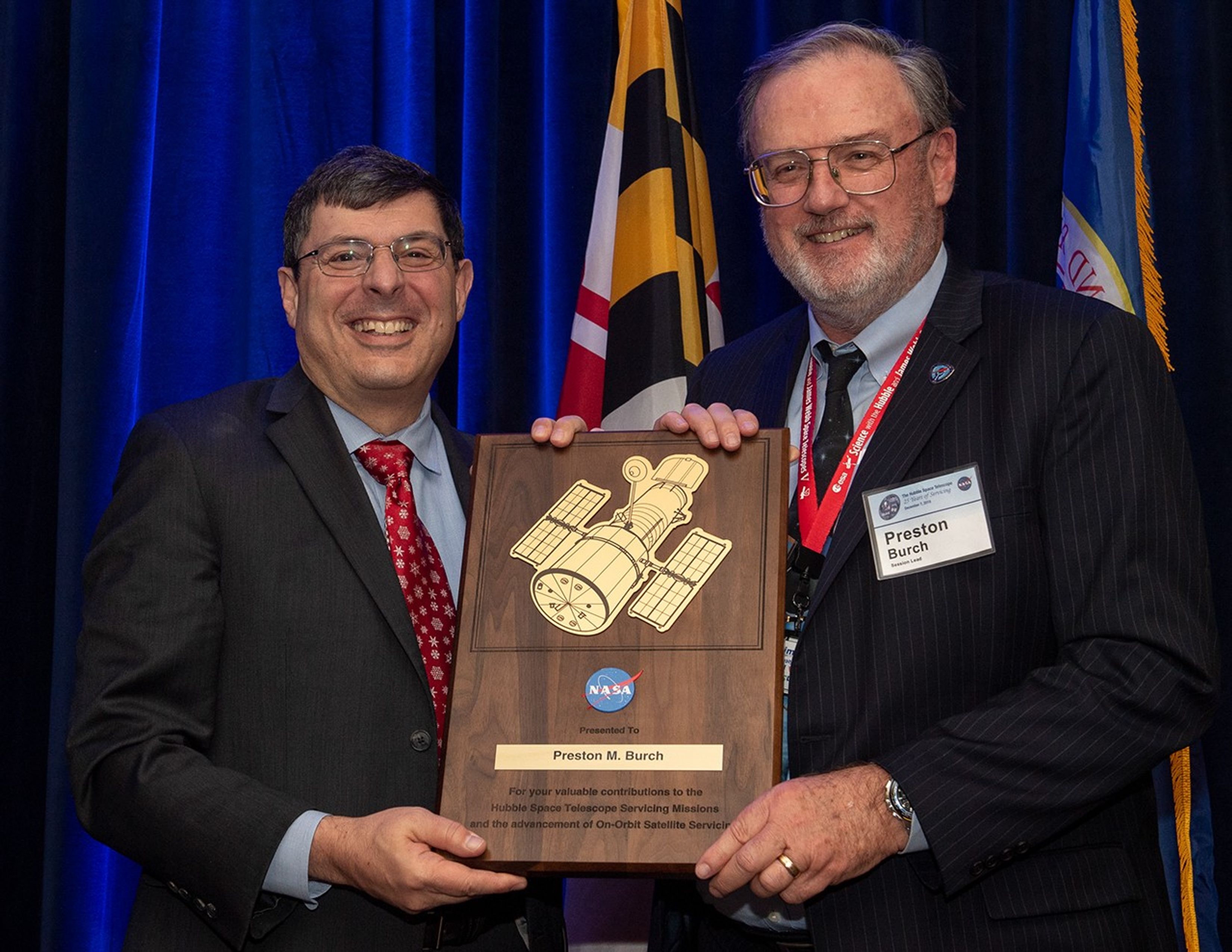 Scolese (left) and Burch (right) hold a wooden plaque between them with Burch's name and a gold graphic of Hubble on it.