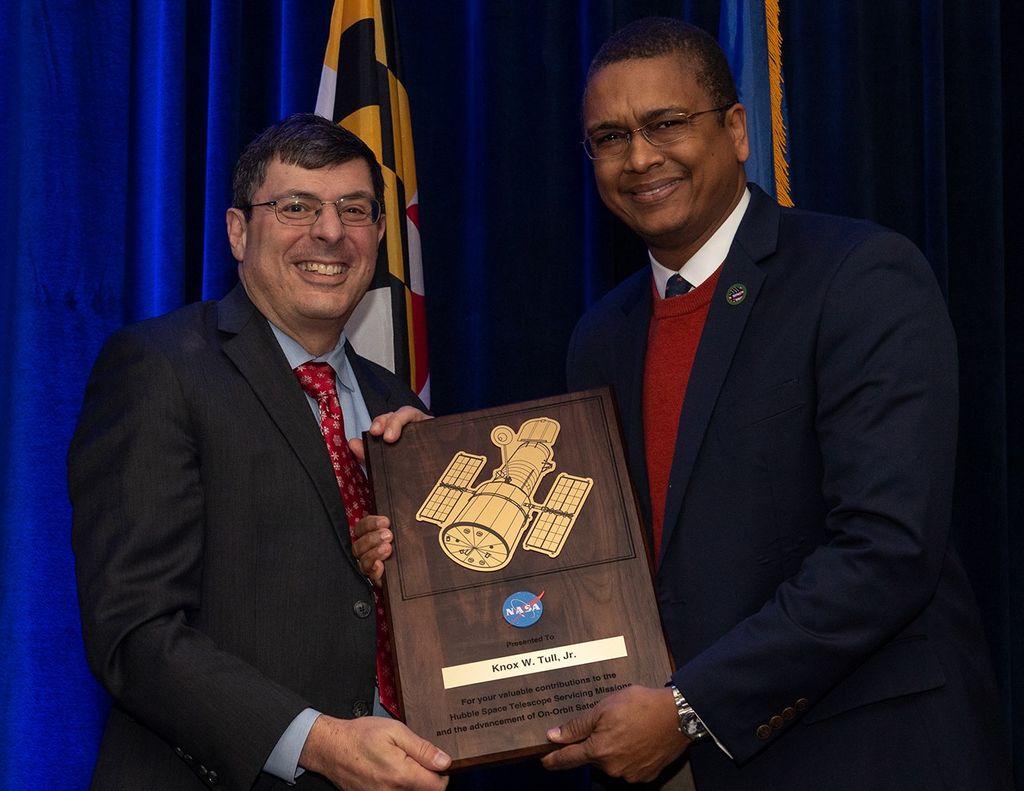 Scolese (left) and Tull (right) hold a wooden plaque between them with Tull's name and a gold graphic of Hubble on it.