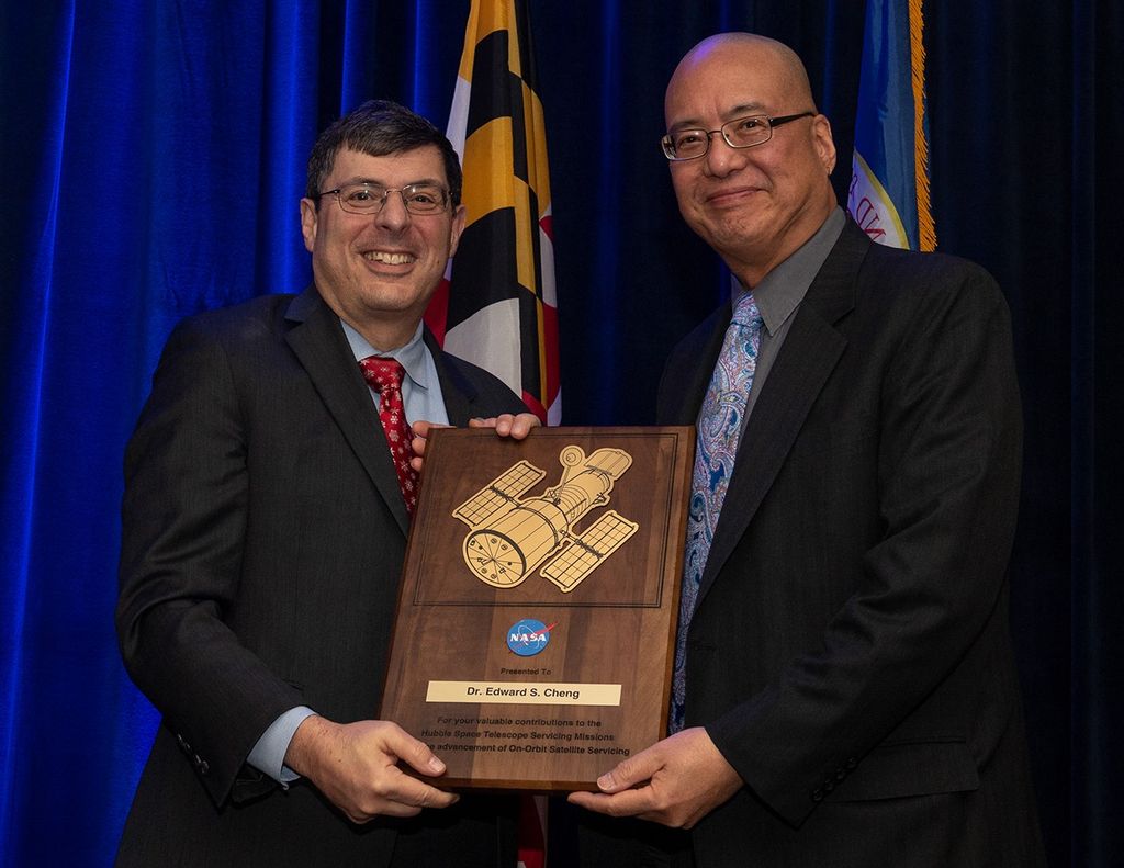 Scolese (left) and Cheng (right) hold a wooden plaque between them with Cheng's name and a gold graphic of Hubble on it.