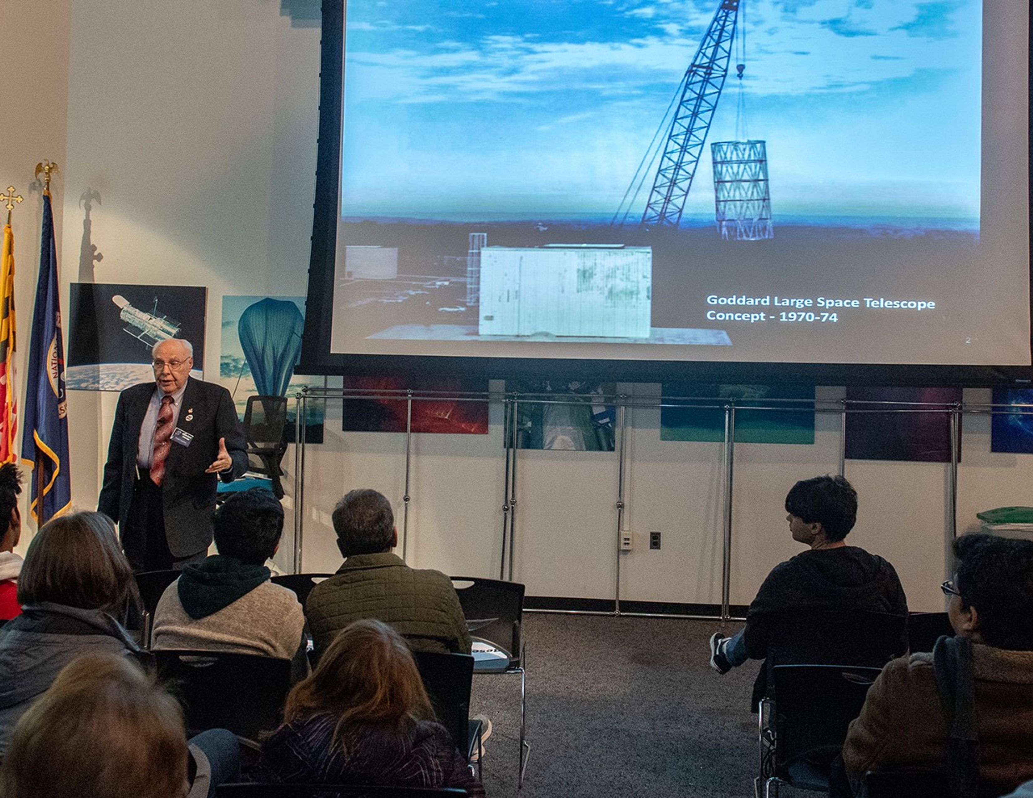 Frank Cepollina, left, speaks to a listening audience, with a photograph projected onto the screen.