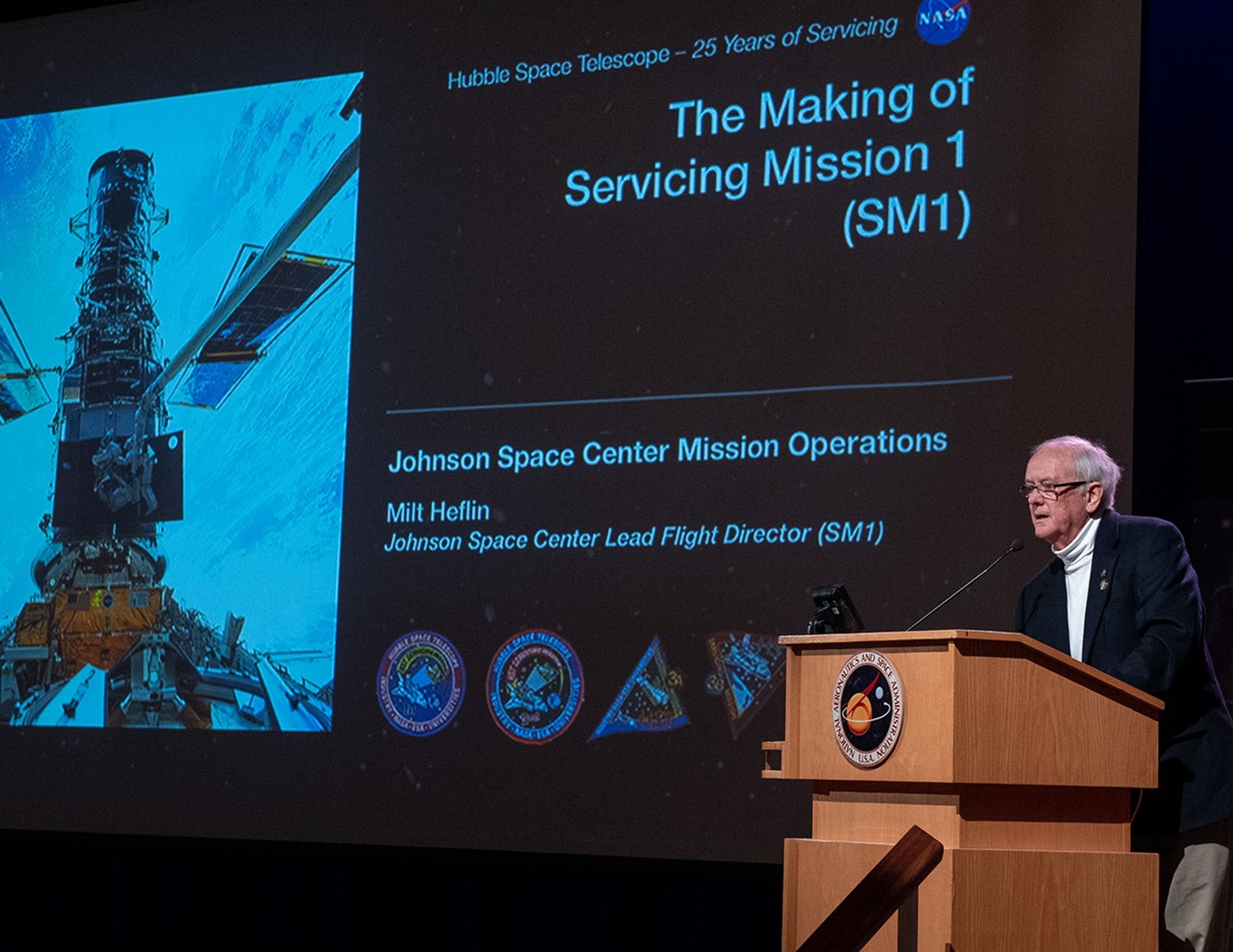 Milton Heflin stands at the podium, addressing the audience.