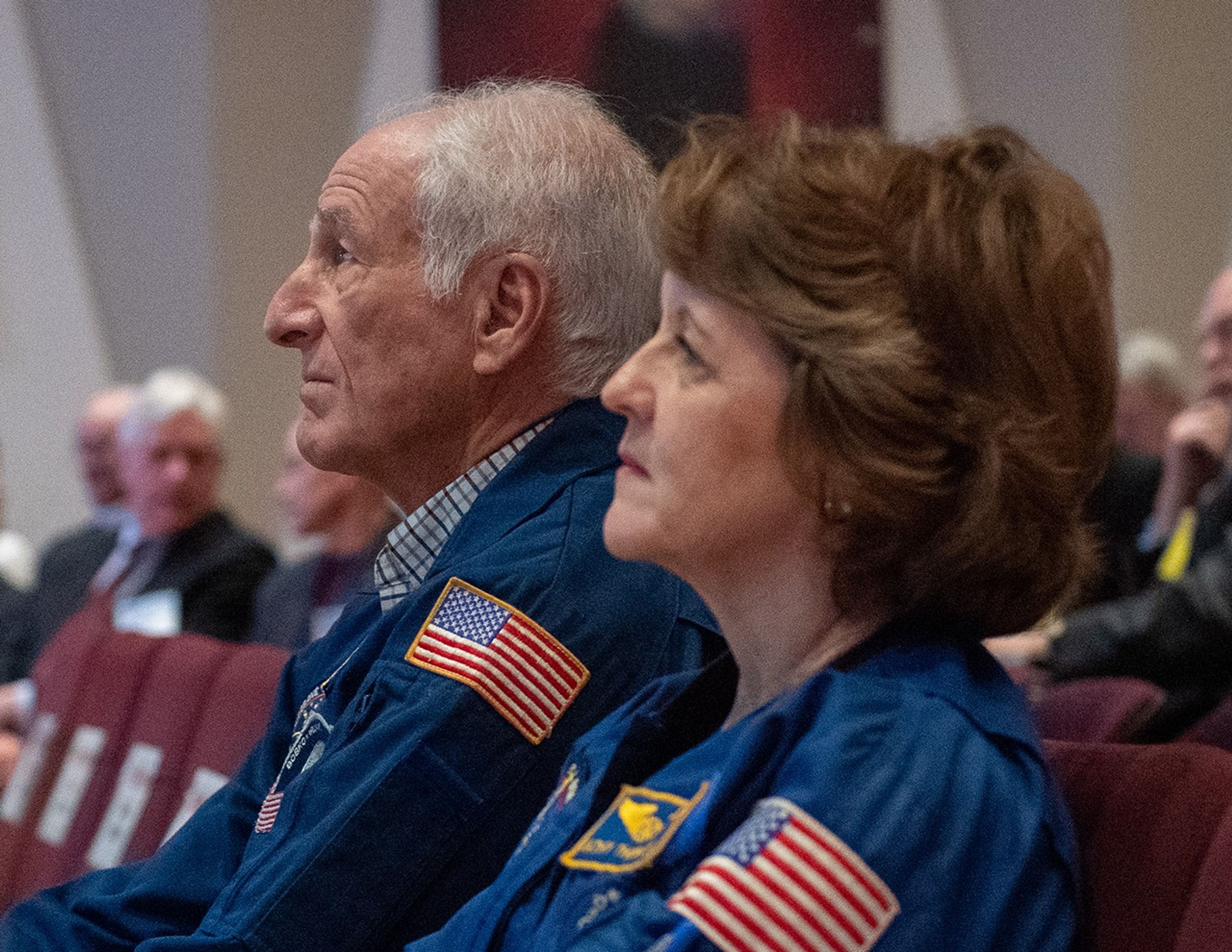 Two astronauts, Jeff Hoffman (left) and Kathy Thornton (right), watch the presentation from the audience.