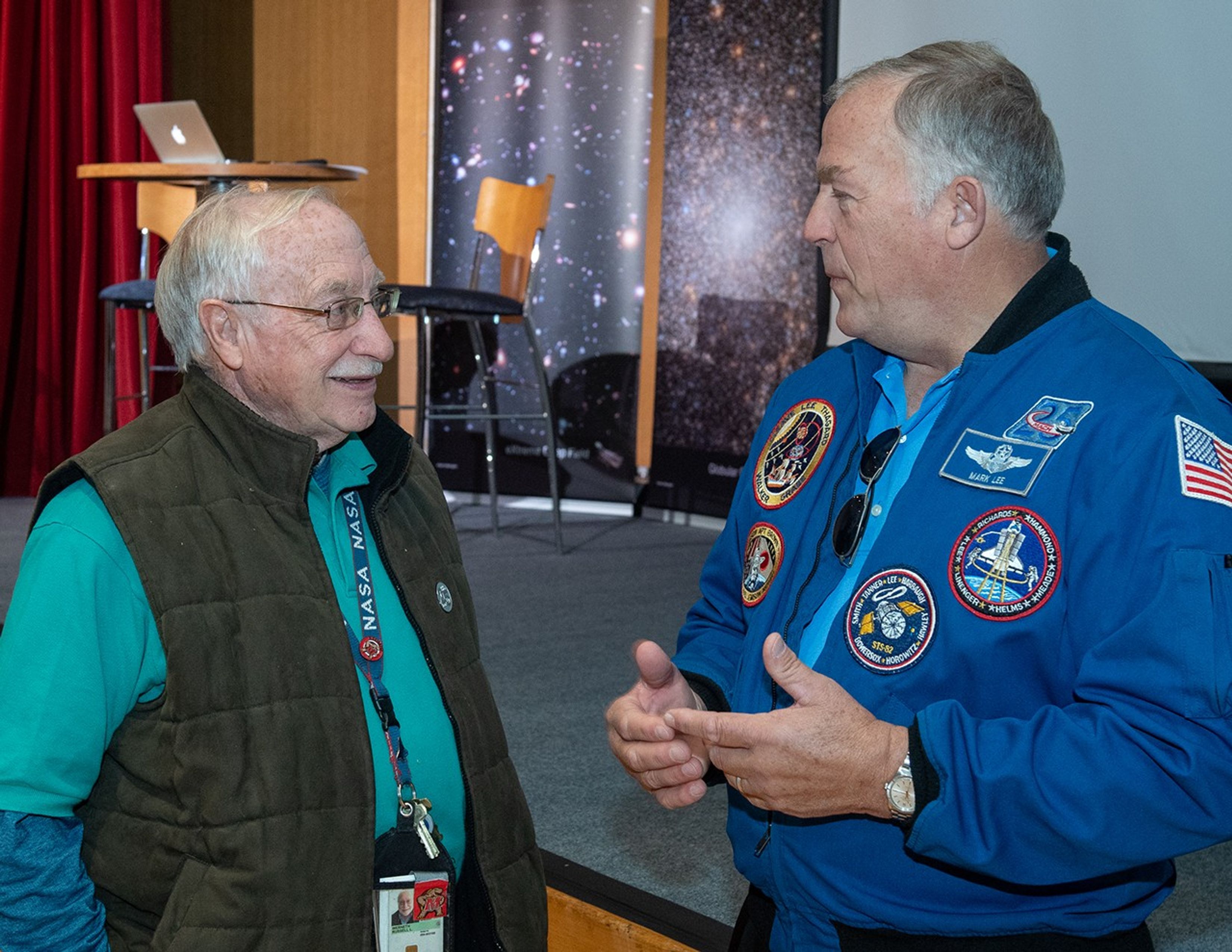 Two men, engineer Russ Werneth (left) and astronaut Mark Lee (right), converse.