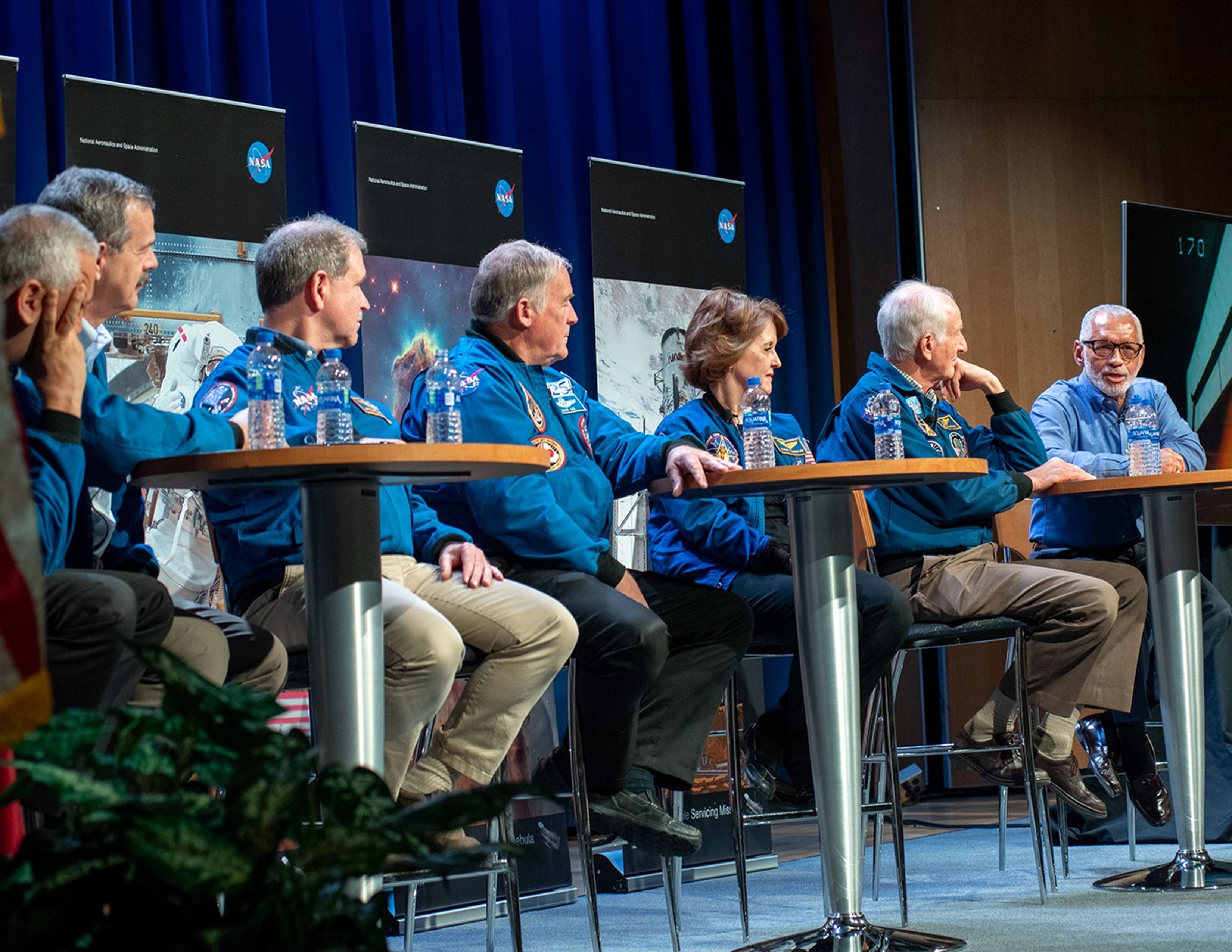Charlie Bolden, far right, speaks on the astronaut panel, while the other six astronauts turn to face him.