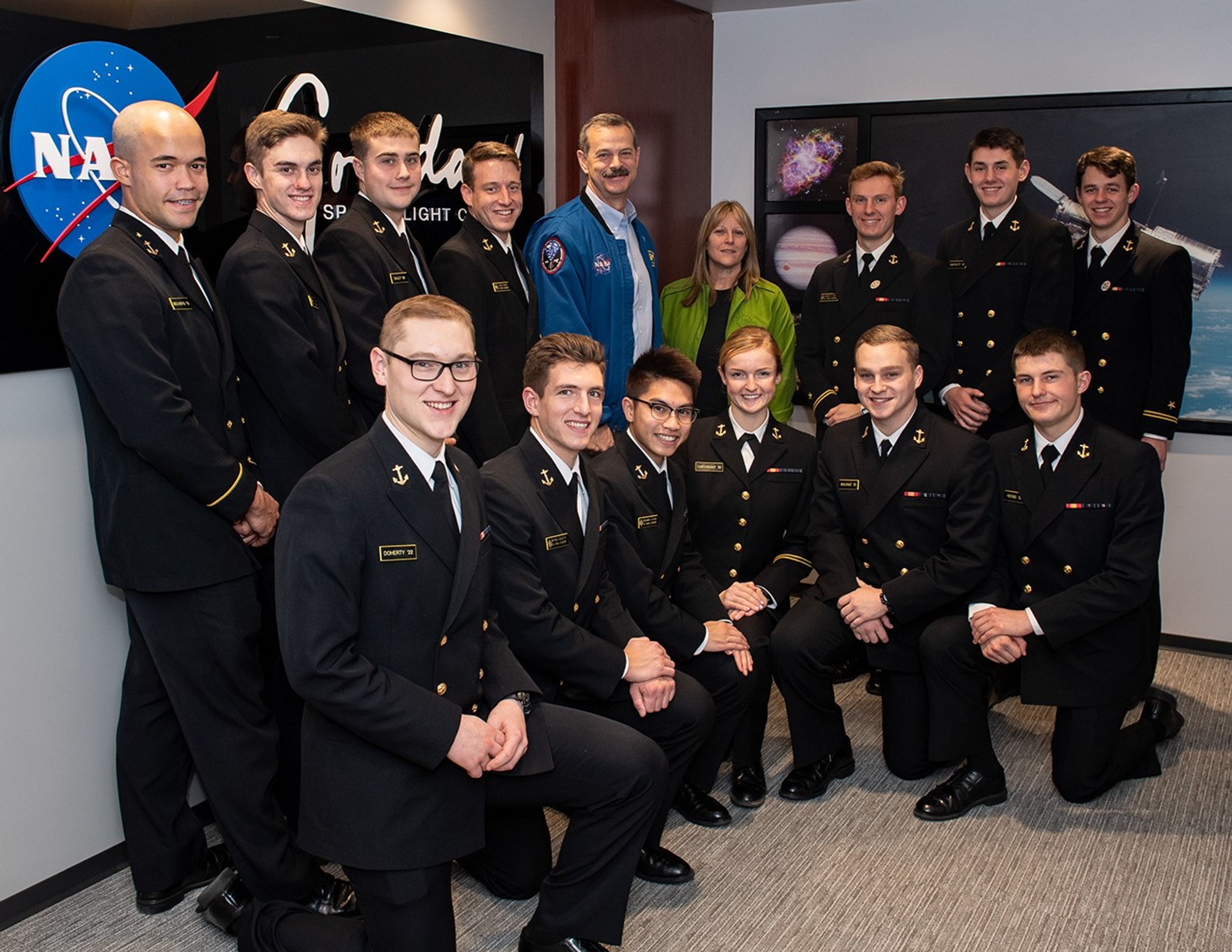Scott Altman and Kay Hire (back center) take a photo with 13 visiting midshipmen (back left, back right, front), 12 men and 1 woman.