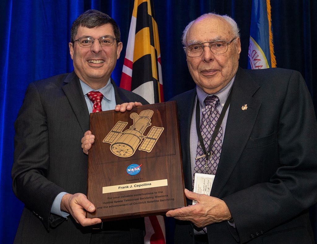 Scolese (left) and Cepollina (right) hold a wooden plaque between them with Cepollina's name and a gold graphic of Hubble on it.