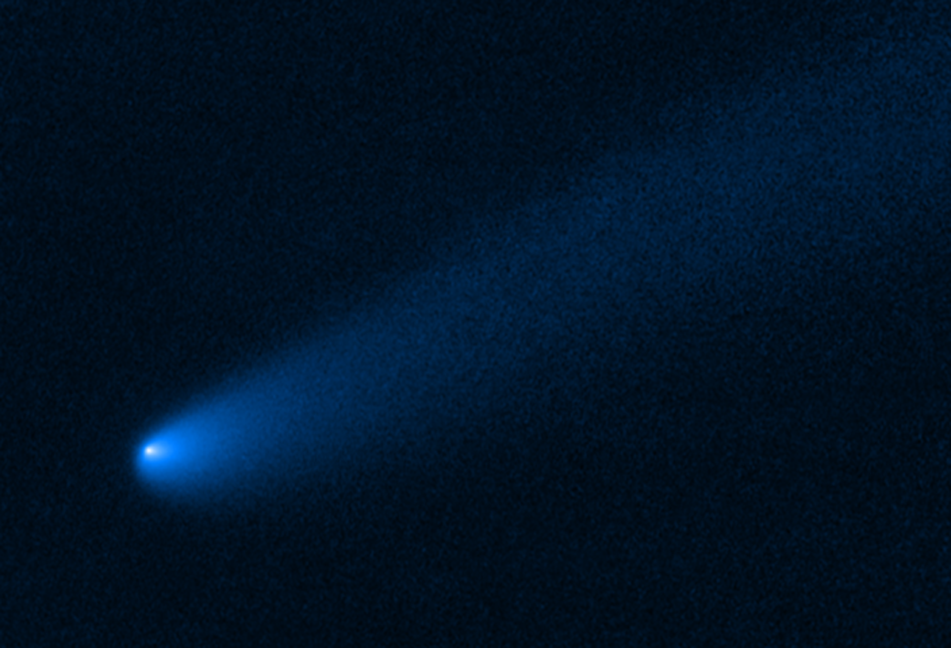 shows a long tail of dust and gas, flowing from the comet's bright solid nucleus in the lower left, toward the upper right.