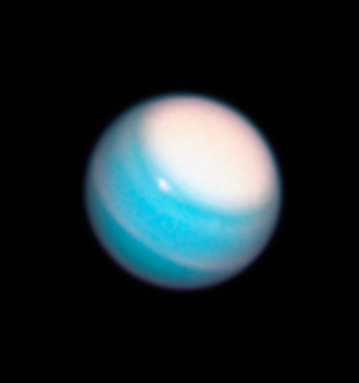 The spherical-shaped planet Uranus. One of its poles, in the upper-right, is a circle of white clouds. The rest of the planet appears a light blue-green, with thin rings of white here and there. Uranus's thin rings are not visible in this image.