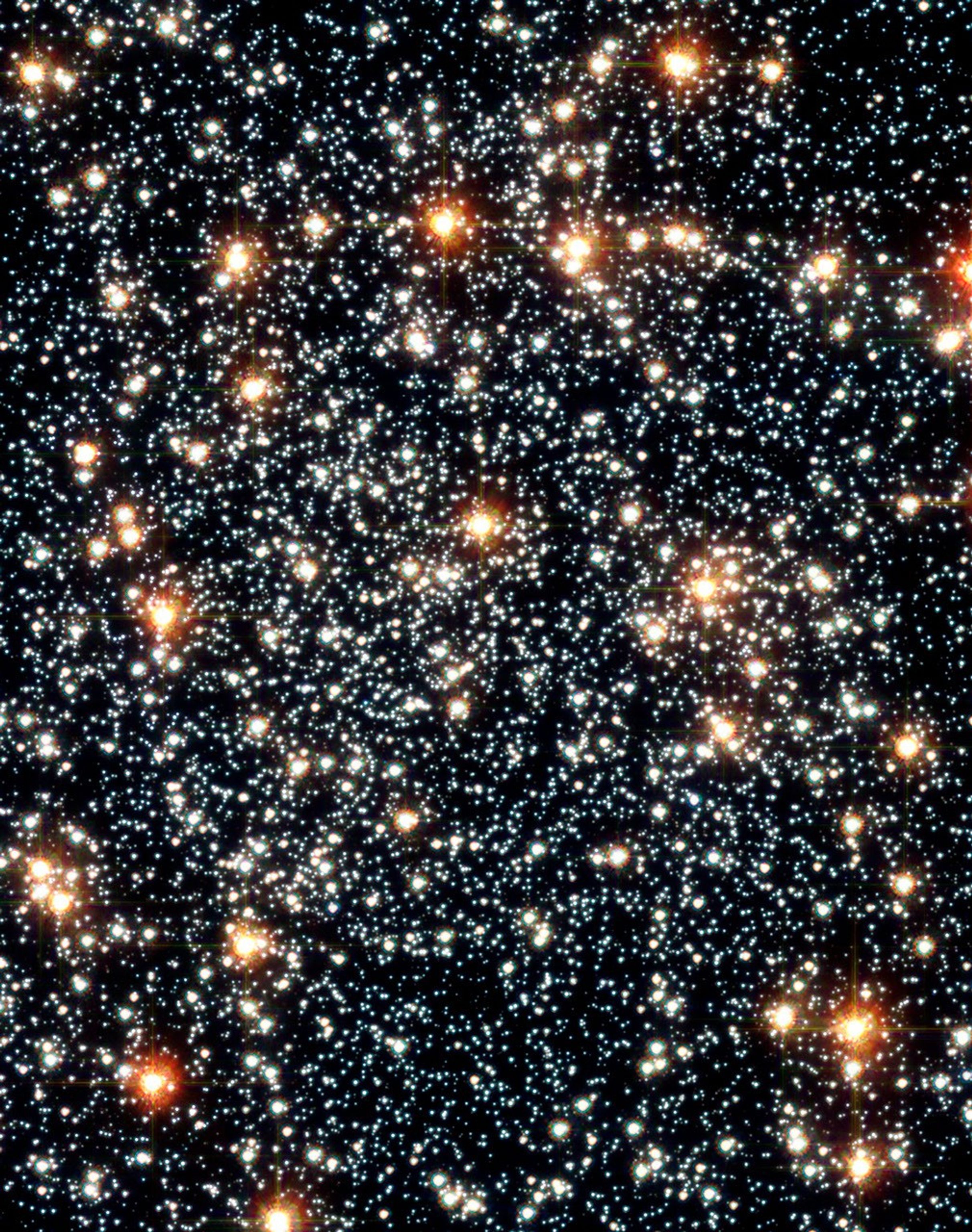 Dozens of red and orange stars shine in the foreground, with thousands more orange, yellow, and white stars in the background.
