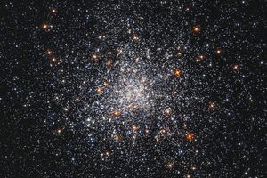 A cluster or white and orange stars, more densely concentrated at the center.
