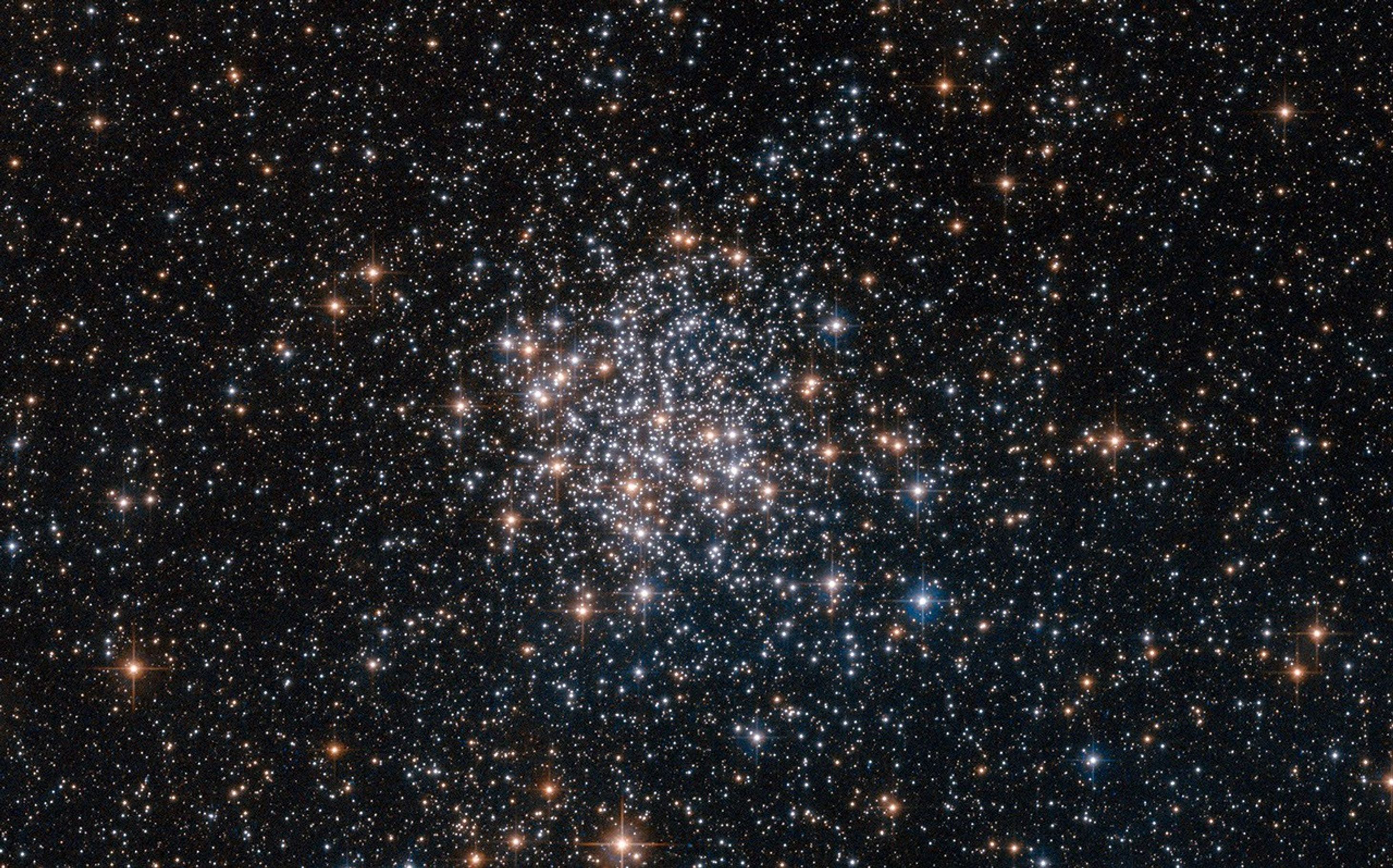 A gathering of red, white and blue stars, more tightly packed near the center of the image. Thousands more stars dot the background