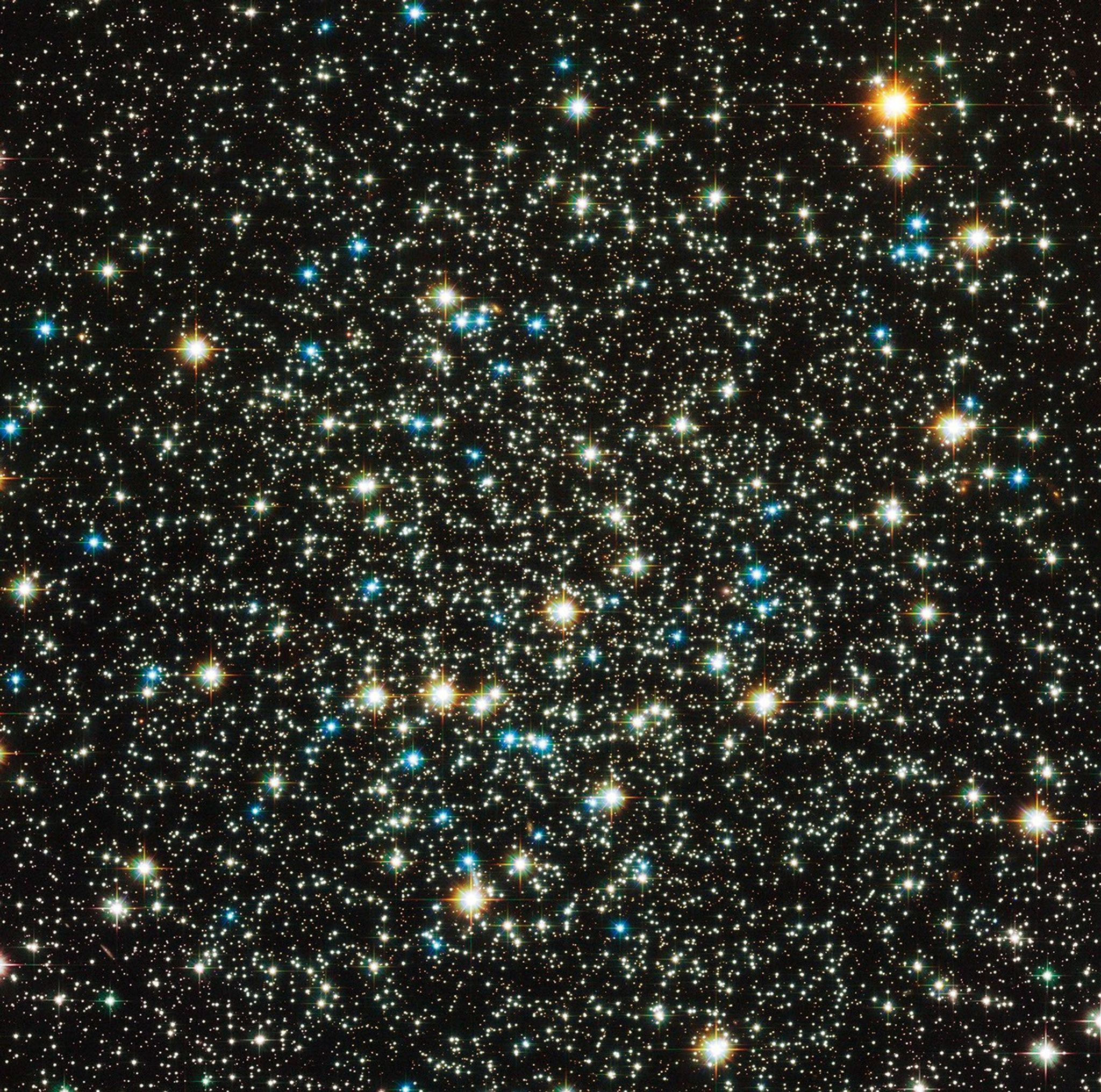 Thousands of stars scattered across a black background. The stars in the foreground appear orange, orange-white, blue, and blue-white.