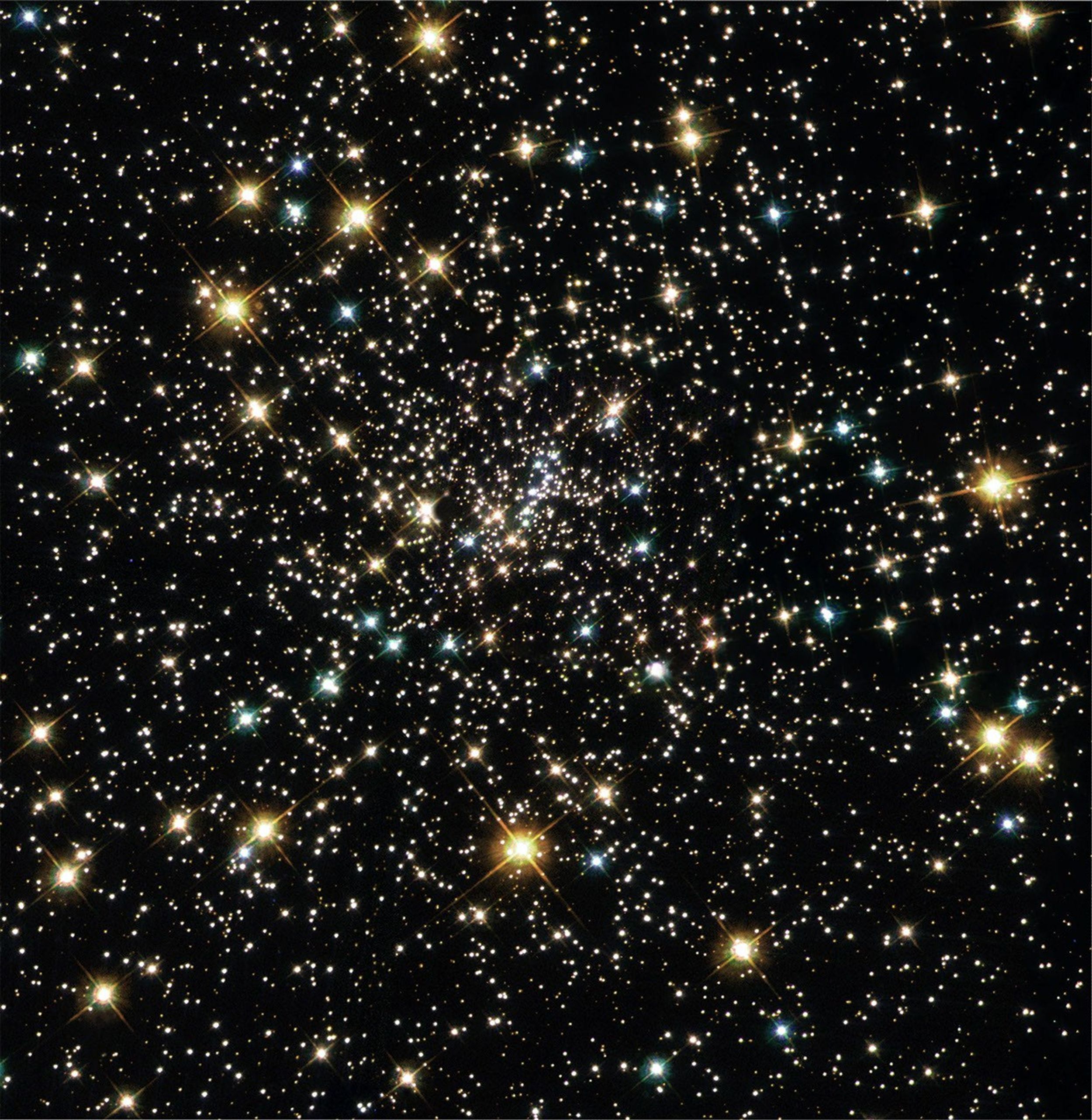 A clustered sprinkle of multi-colored stars: yellow in the foreground, blue-white farther away, and white stars in the background.