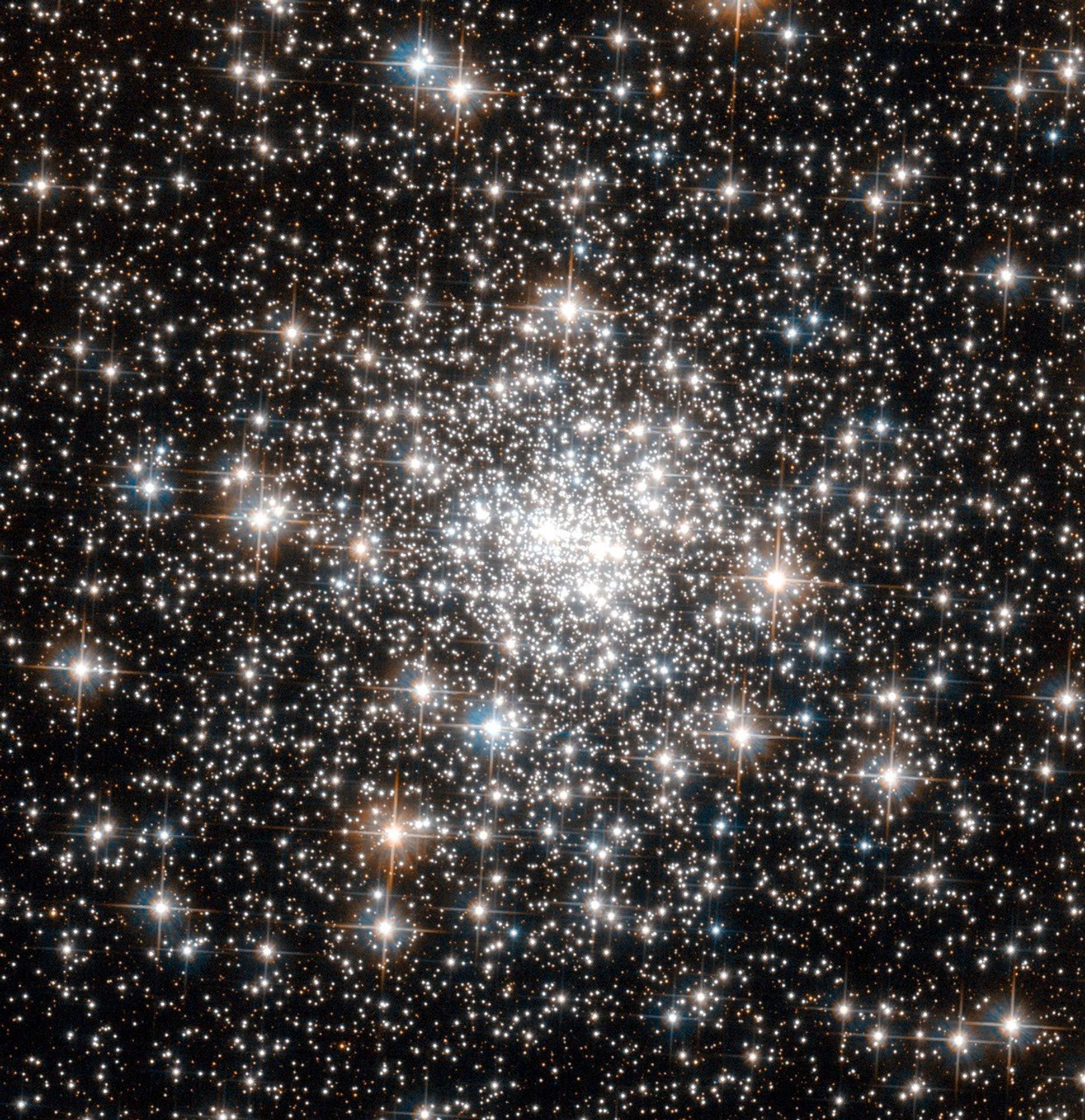 Thousands of bright white and reddish-white stars, packed tightly together near the center and becoming more scattered farther out.