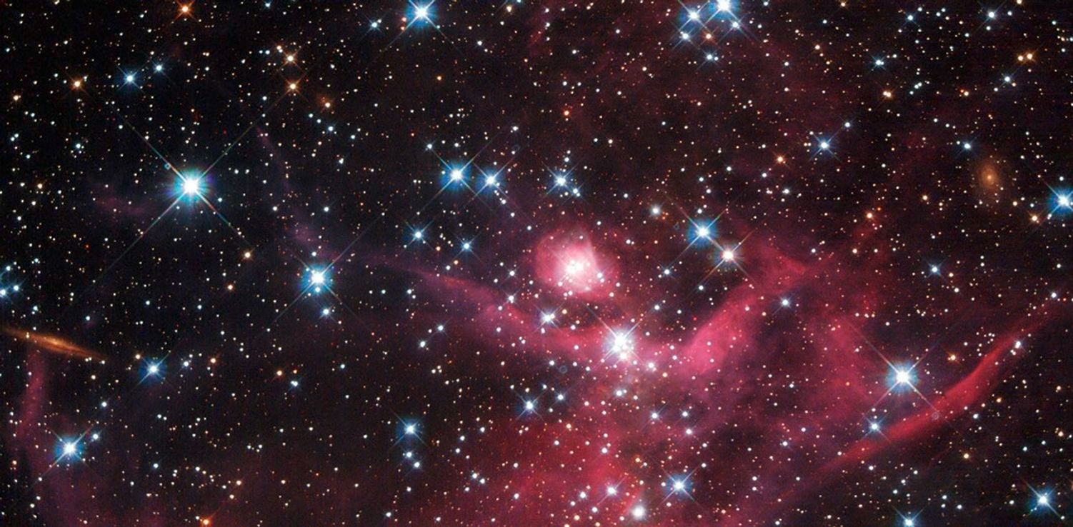 Dazzling blue stars amid swaths of magenta gas and dust.