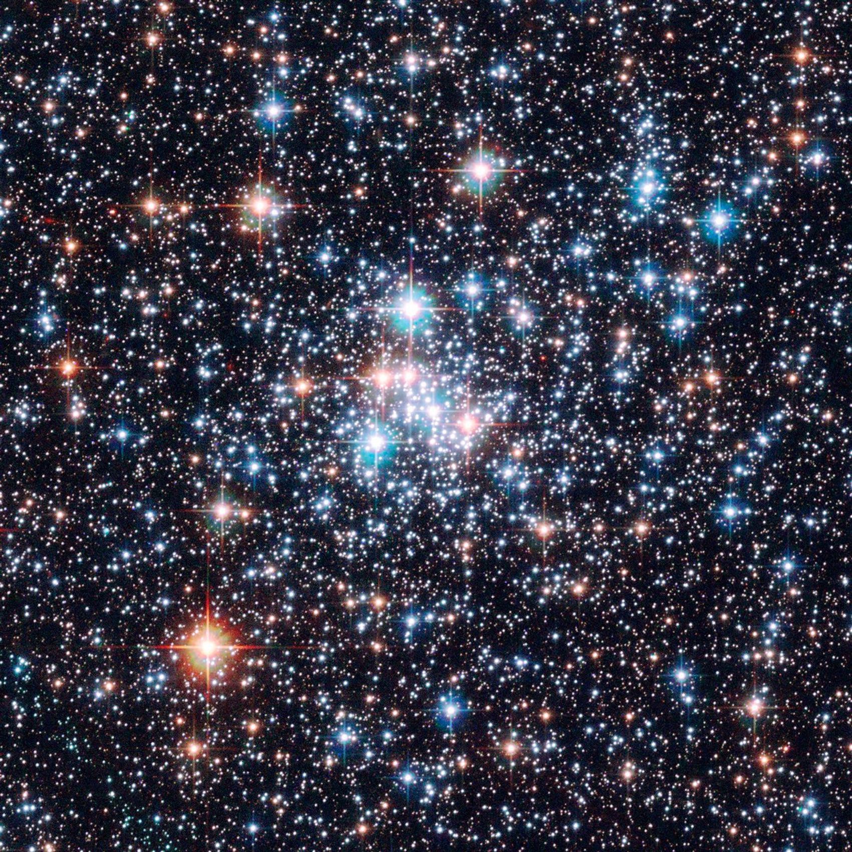 Blue and red stars shine in the foreground, with thousands more stars of all colors (mainly red, orange, white, and blue) in the background.