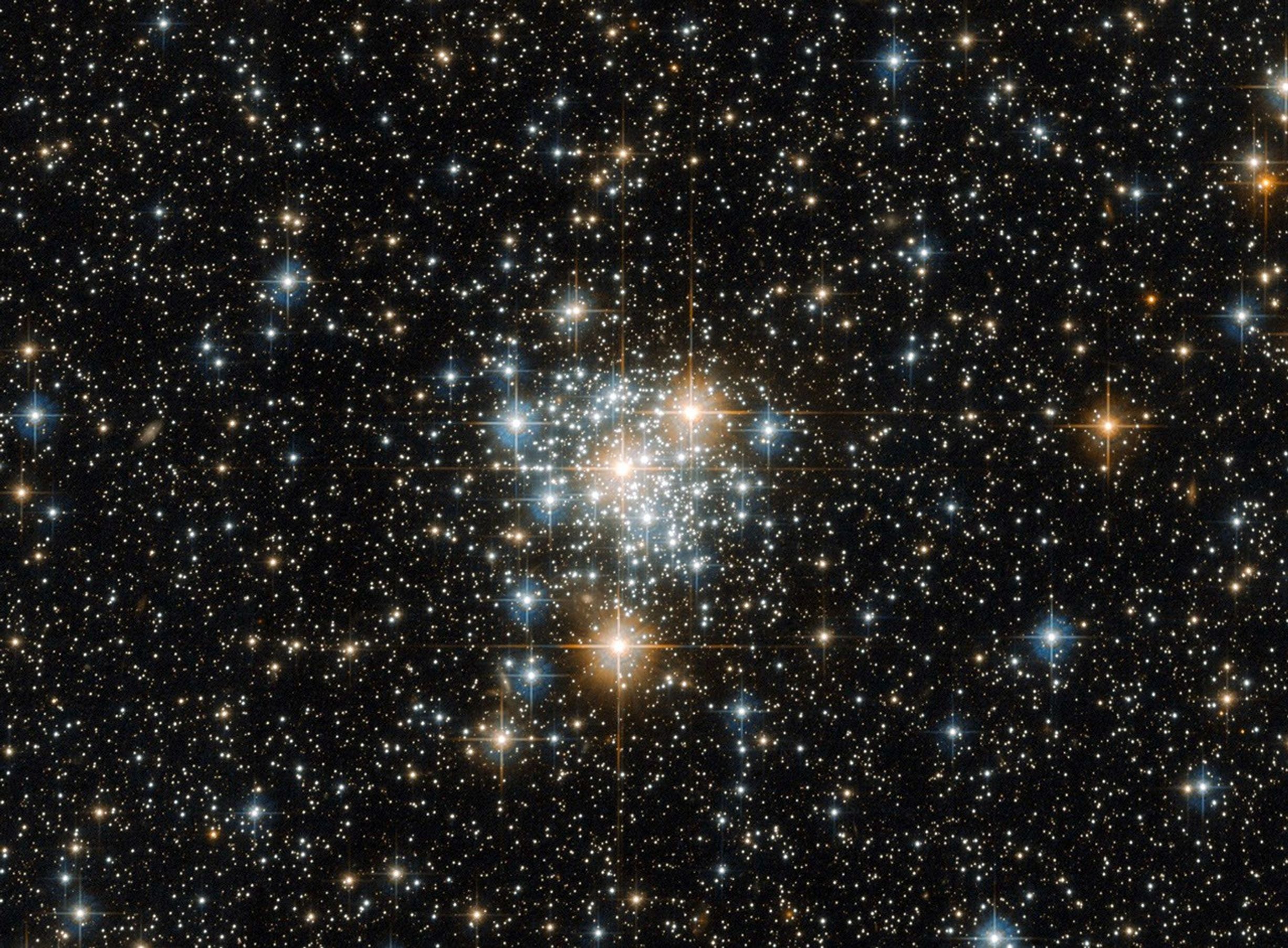 Bright cluster of white, blue-white, and red-orange stars on a dark starfield