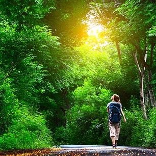 Young woman walking on green asphalt road in forest