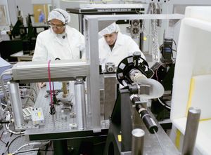 Two clean room technicians working with optical testing and calibration equipment for Landsat 4.
