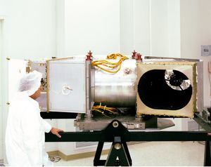 Technician in clean room attire inspecting the Thematic Mapper instrument during pre-launch preparation, showing the scanning aperture and internal components before installation on the Landsat 4 satellite.