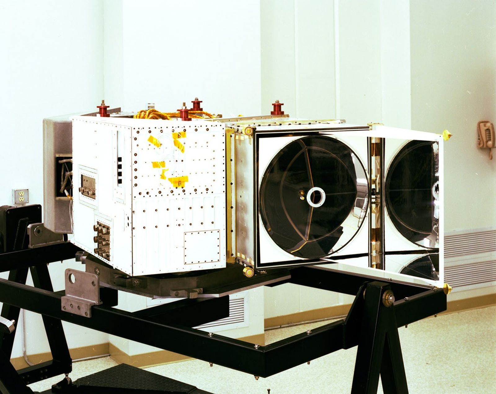 Landsat 4 Thematic Mapper instrument on test stand with open housing showing internal circular scanning mirror assembly.