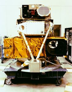 Bottom view of Landsat 4 satellite during assembly, showing gold thermal blankets, white structural elements, and instrument components including circular aperture.
