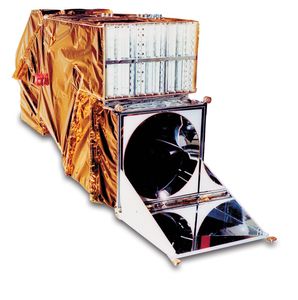 Side view of the Thematic Mapper instrument model displaying the gold thermal protection, exposed detector arrays, and scanning mirror mechanism used for capturing multispectral Earth imagery.