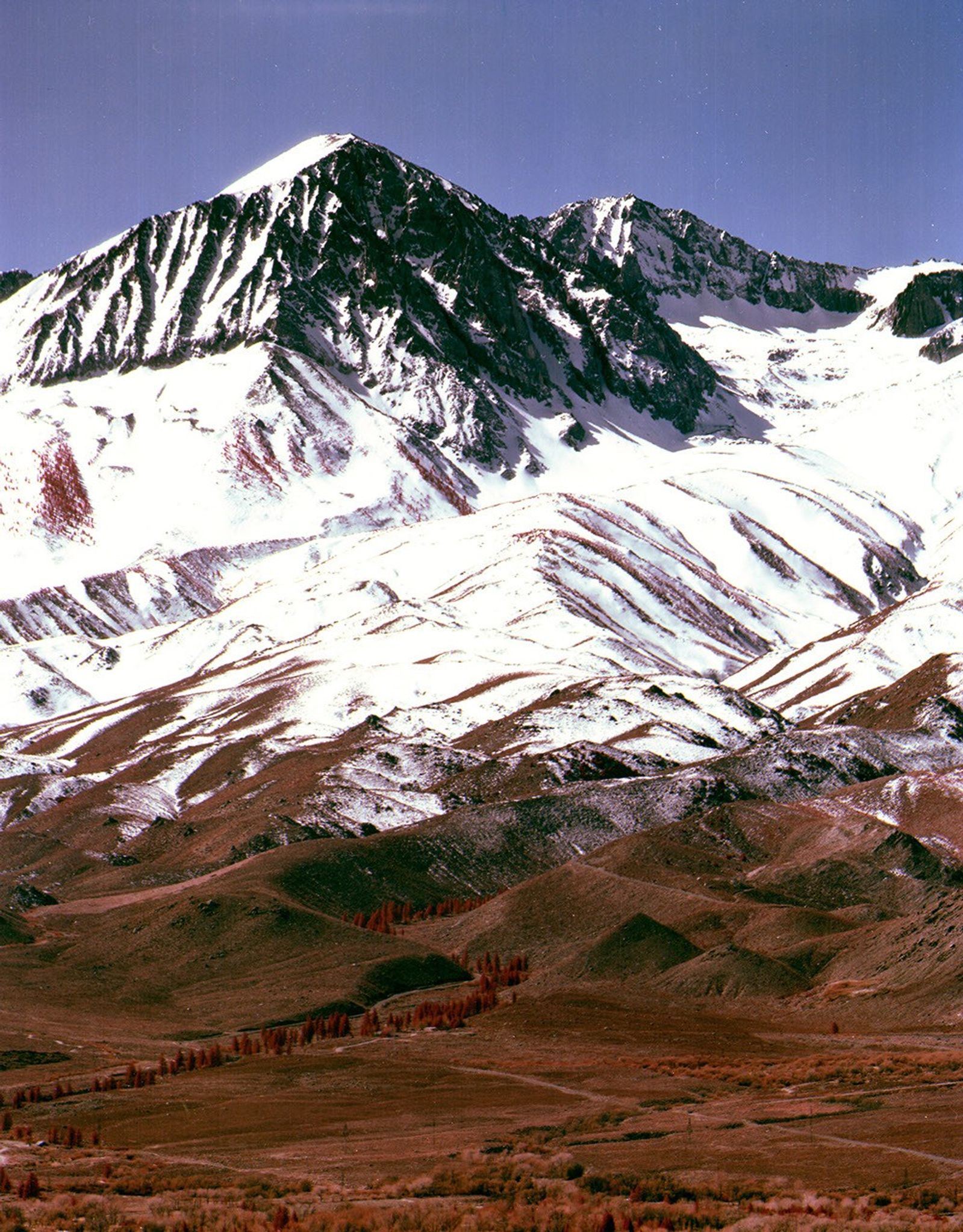 Landsat 5 Thematic Mapper image of Birch Mountain in the Sierra Nevada, showing snow-capped peaks and layered sedimentary rock formations with exposed geological stratification.