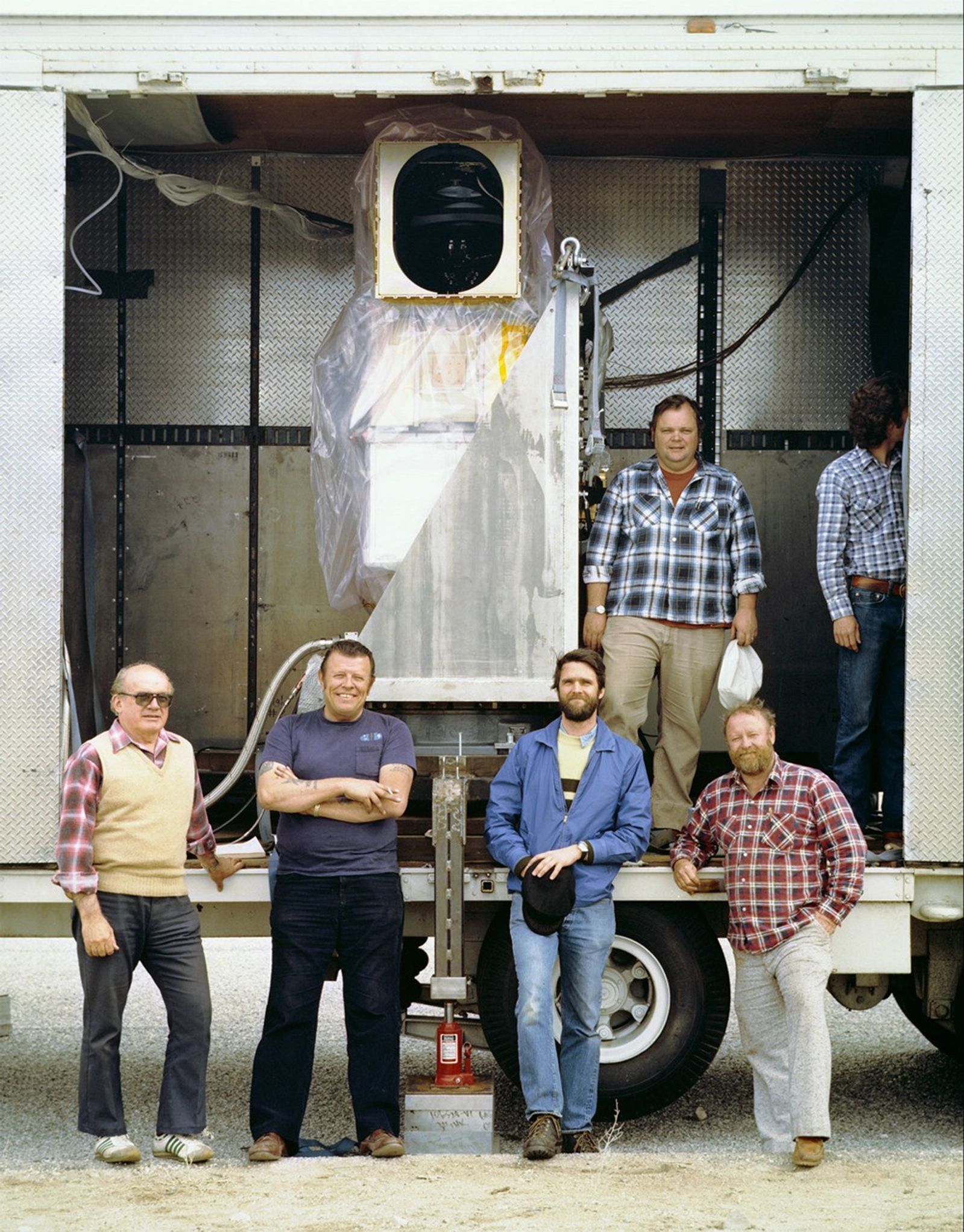 Team members posing with Landsat 5 TM receiving equipment housed in mobile trailer during field operations.