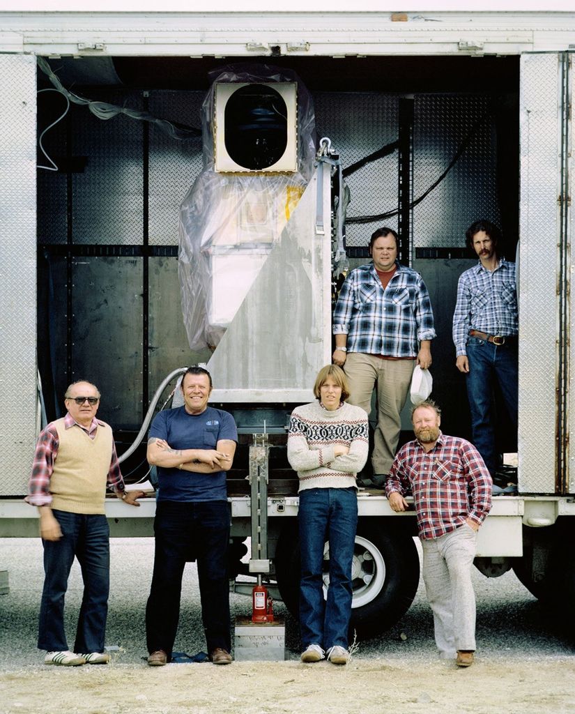Team members posing with Landsat 5 TM receiving equipment housed in mobile trailer during field operations.