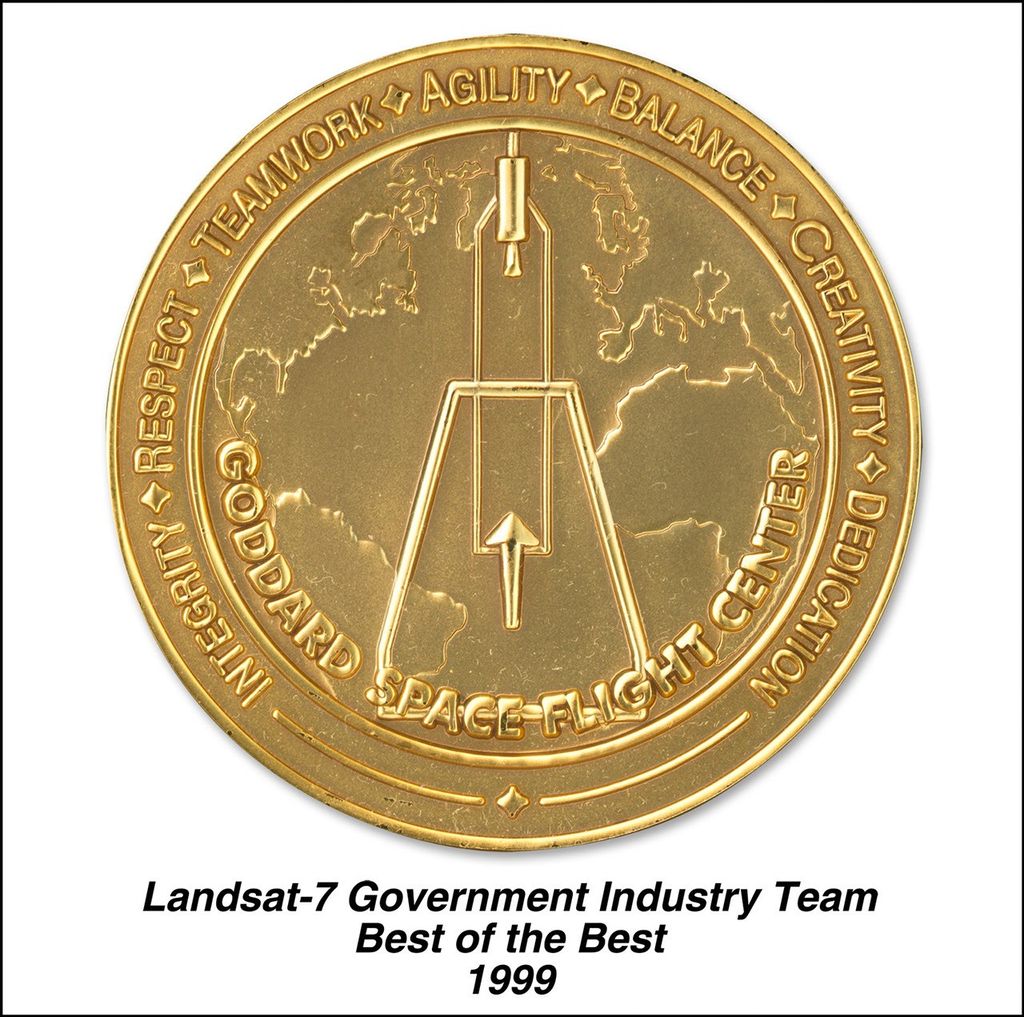 Gold commemorative medal for the Landsat-7 Government Industry Team. The circular medal features a stylized rocket or launch vehicle design in the center, positioned over an outline map of Earth's continents. Around the outer ring are the words 'RESPECT', 'TEAMWORK', 'AGILITY', 'BALANCE', 'CREATIVITY', 'DEDICATION', and 'INTEGRITY' separated by diamond symbols. The phrase 'GODDARD SPACE FLIGHT CENTER' spans the bottom portion. Below the medal is text reading 'Landsat-7 Government Industry Team Best of the Best 1999'.