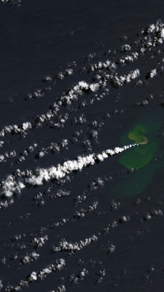 A Landsat satellite image featuring a faint green island with puffy white smoke pouring out across the image